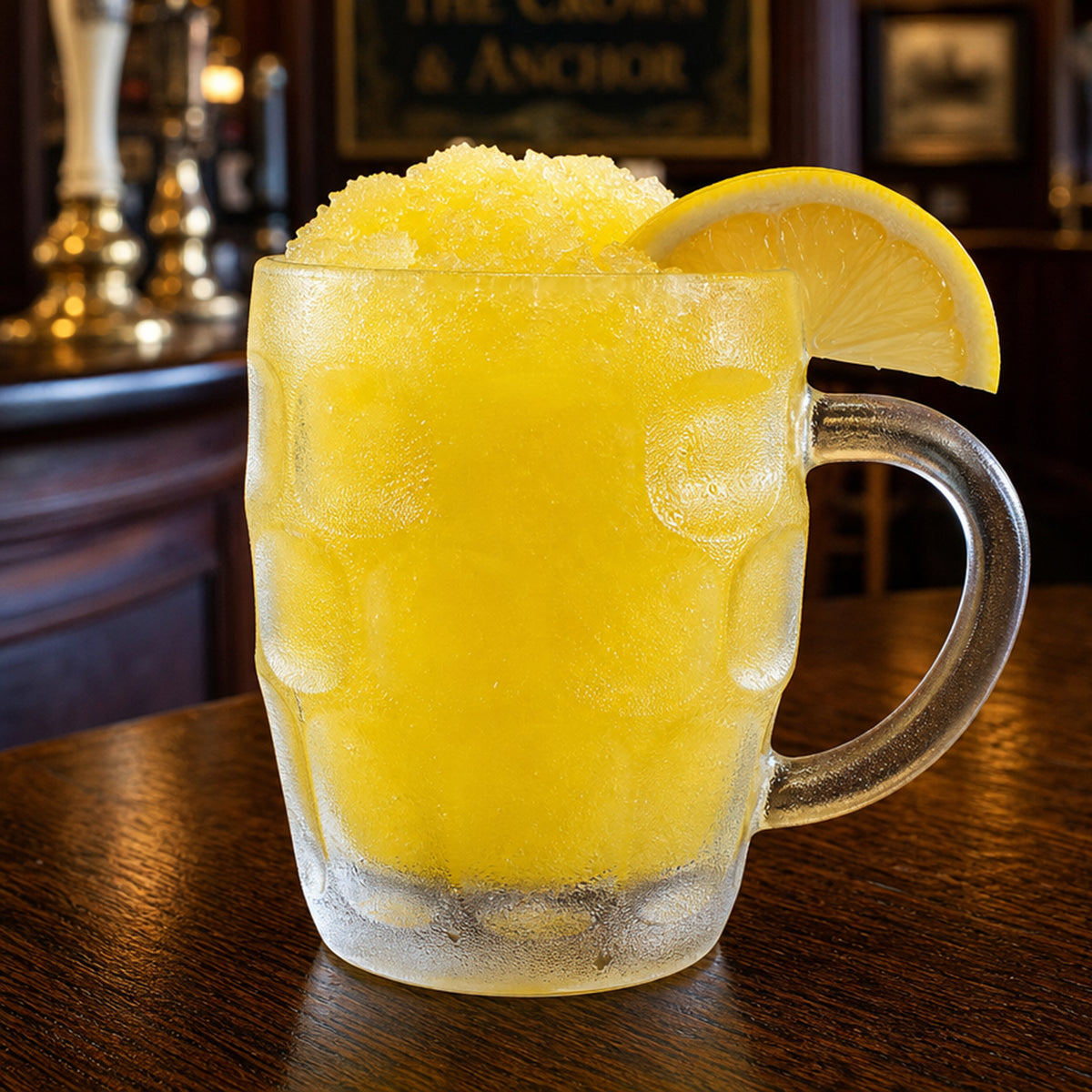 A frosted glass mug filled with a bright yellow slushy drink, topped with crushed ice and garnished with a lemon wedge, set on a wooden bar table in a pub interior.