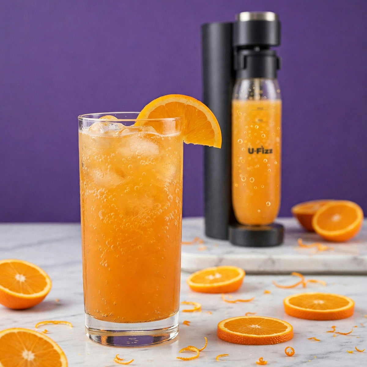 A tall glass of orange soda with ice and an orange slice garnish sits on a marble surface, with a carbonator bottle labeled U-Fizz behind it and orange slices scattered around against a purple background.