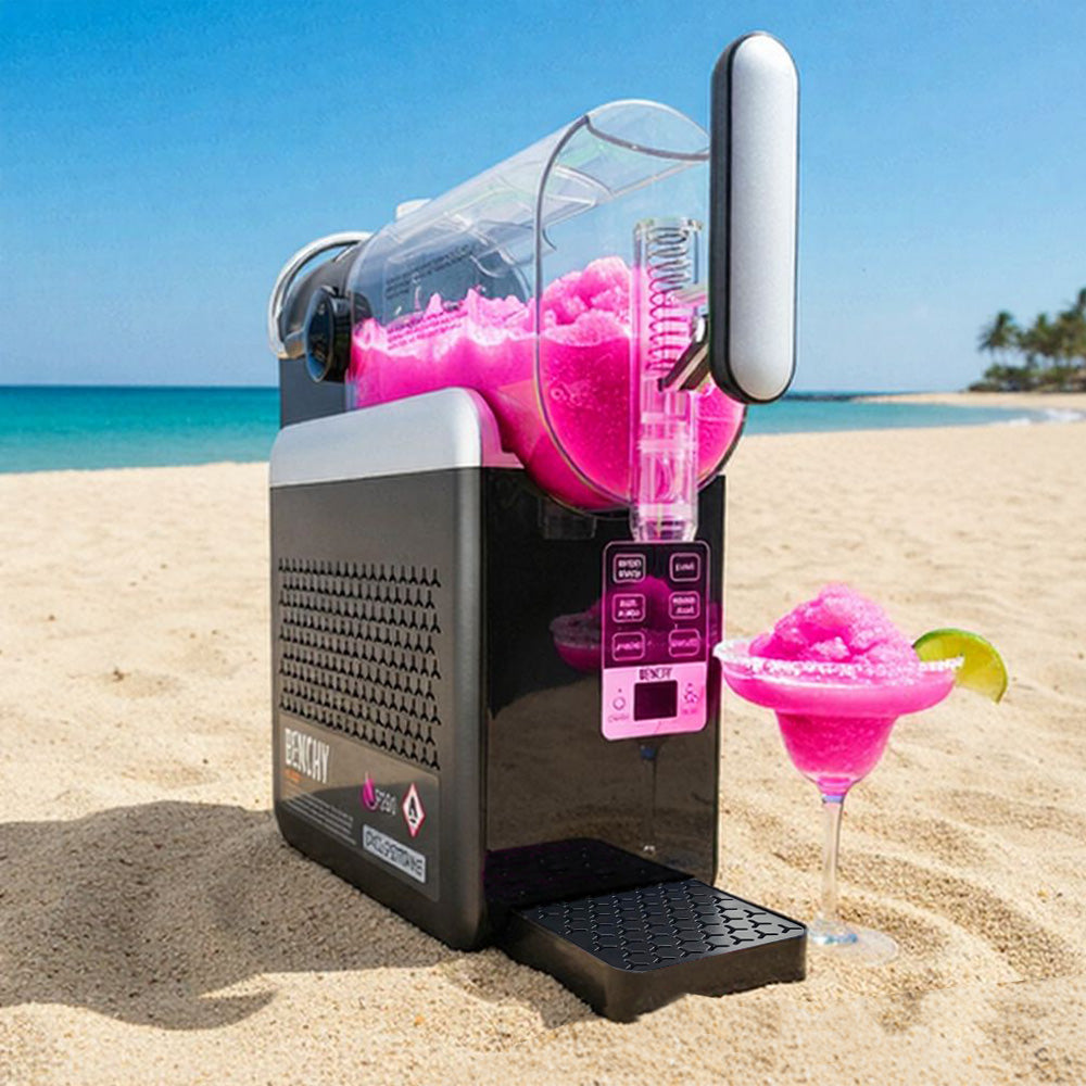 Pink slushy machine on a beach with pink slushie and lime garnish.